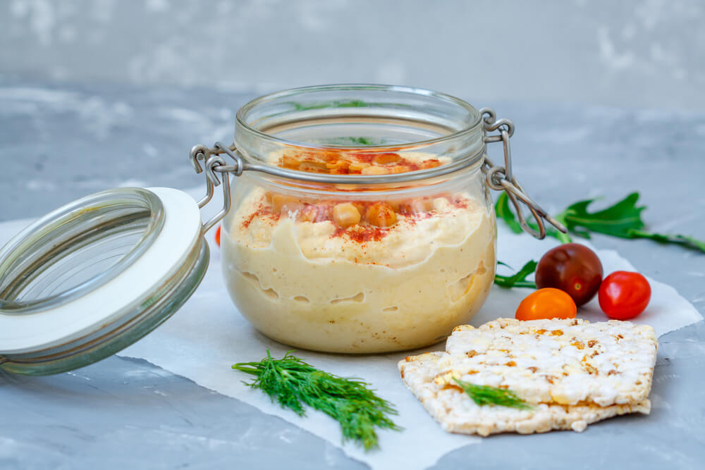 Hummus ve sklenici s krekry a rajčaty